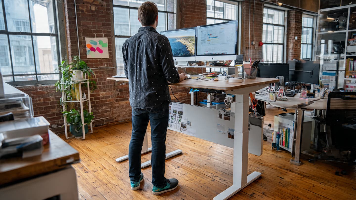 Person standing at an ergonomic standing desk with proper posture